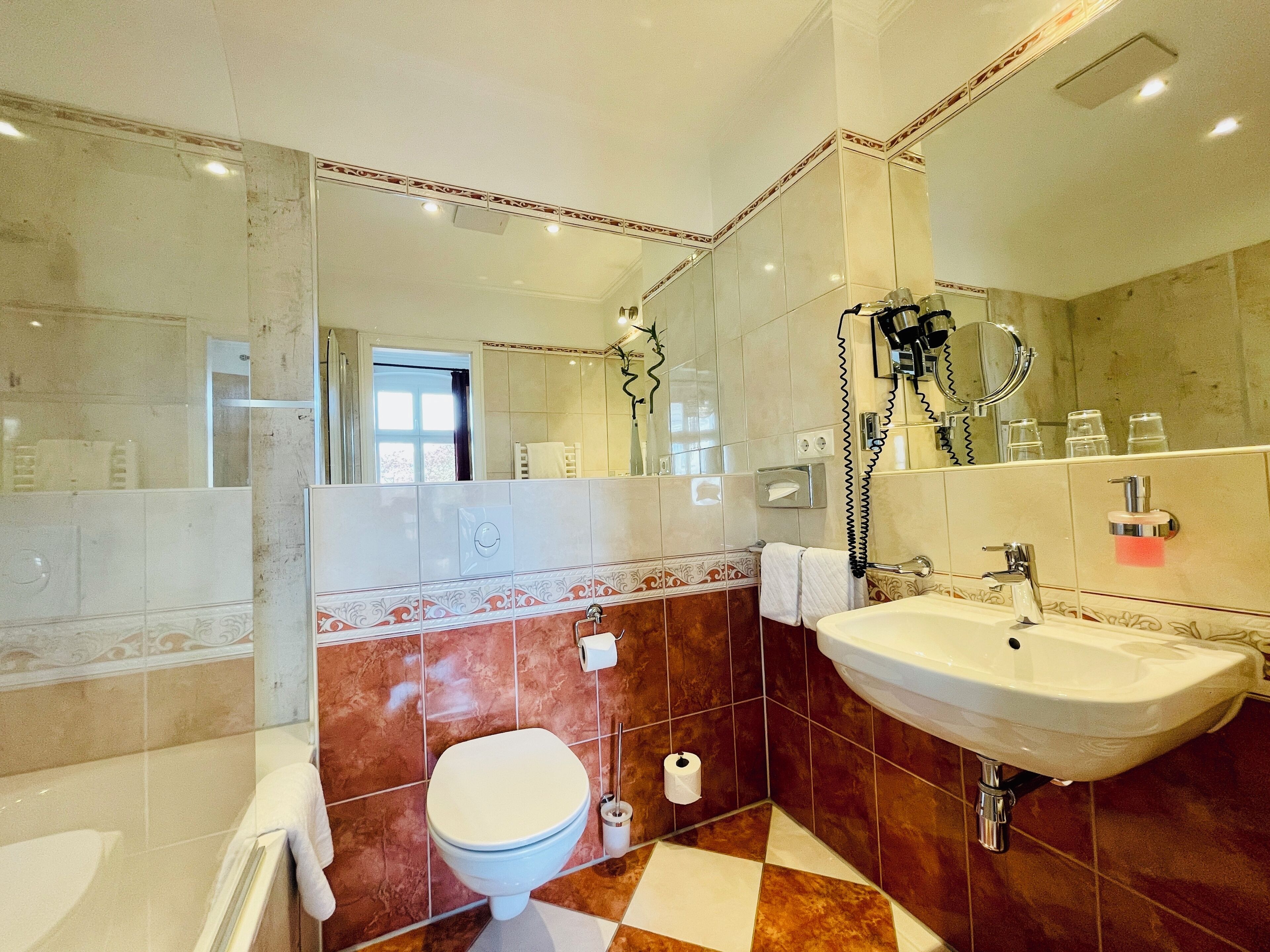 A bathroom with a toilet, sink, and mirror.