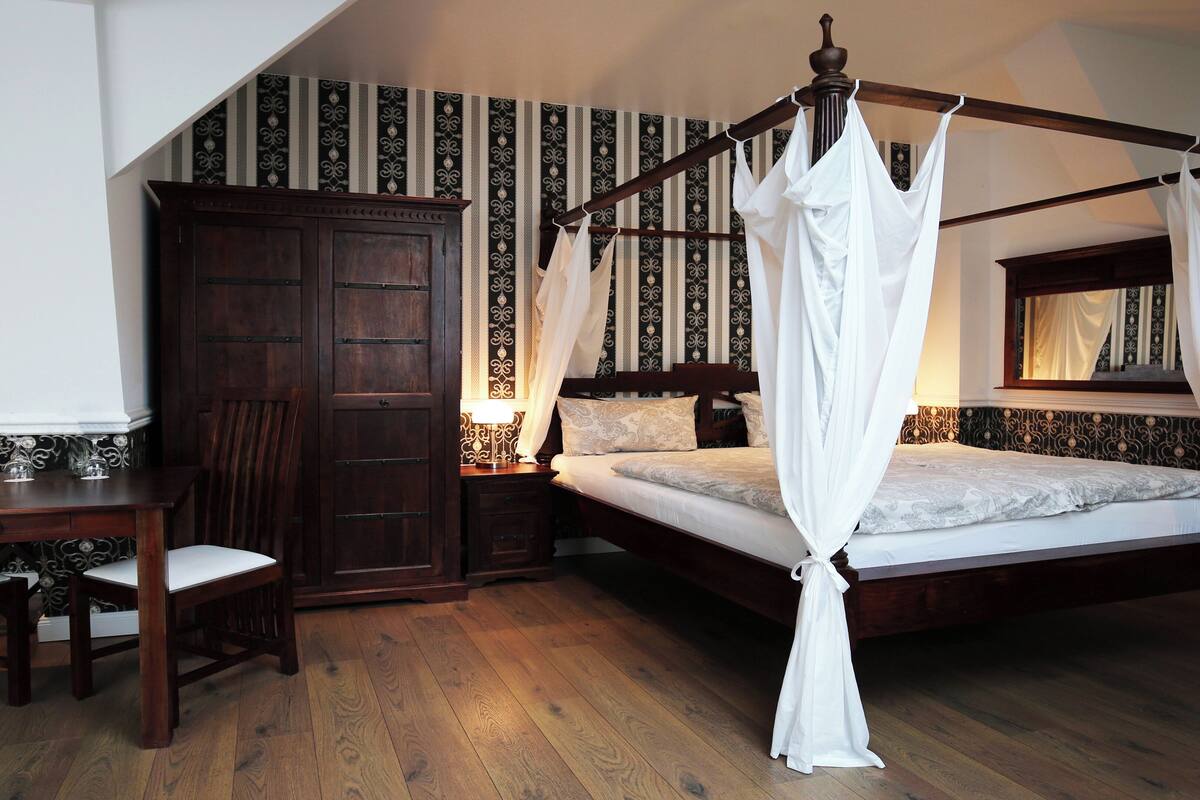 Un dormitorio con cama con dosel, suelo de madera y un amplio armario.