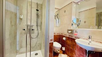 A bathroom with a glass-enclosed shower, a white sink, and a toilet.