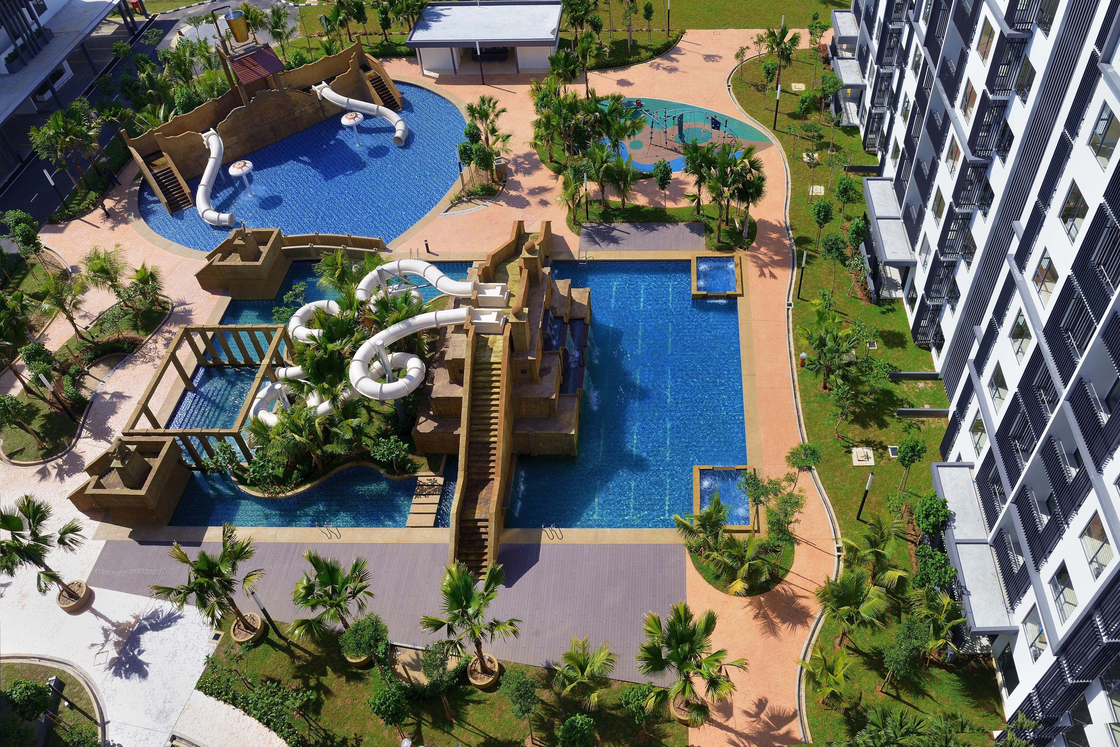 An aerial view of a resort with multiple swimming pools, water slides, and palm trees.