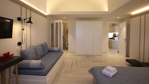 A modern bedroom with a sofa, a bed, and a walk-in closet.