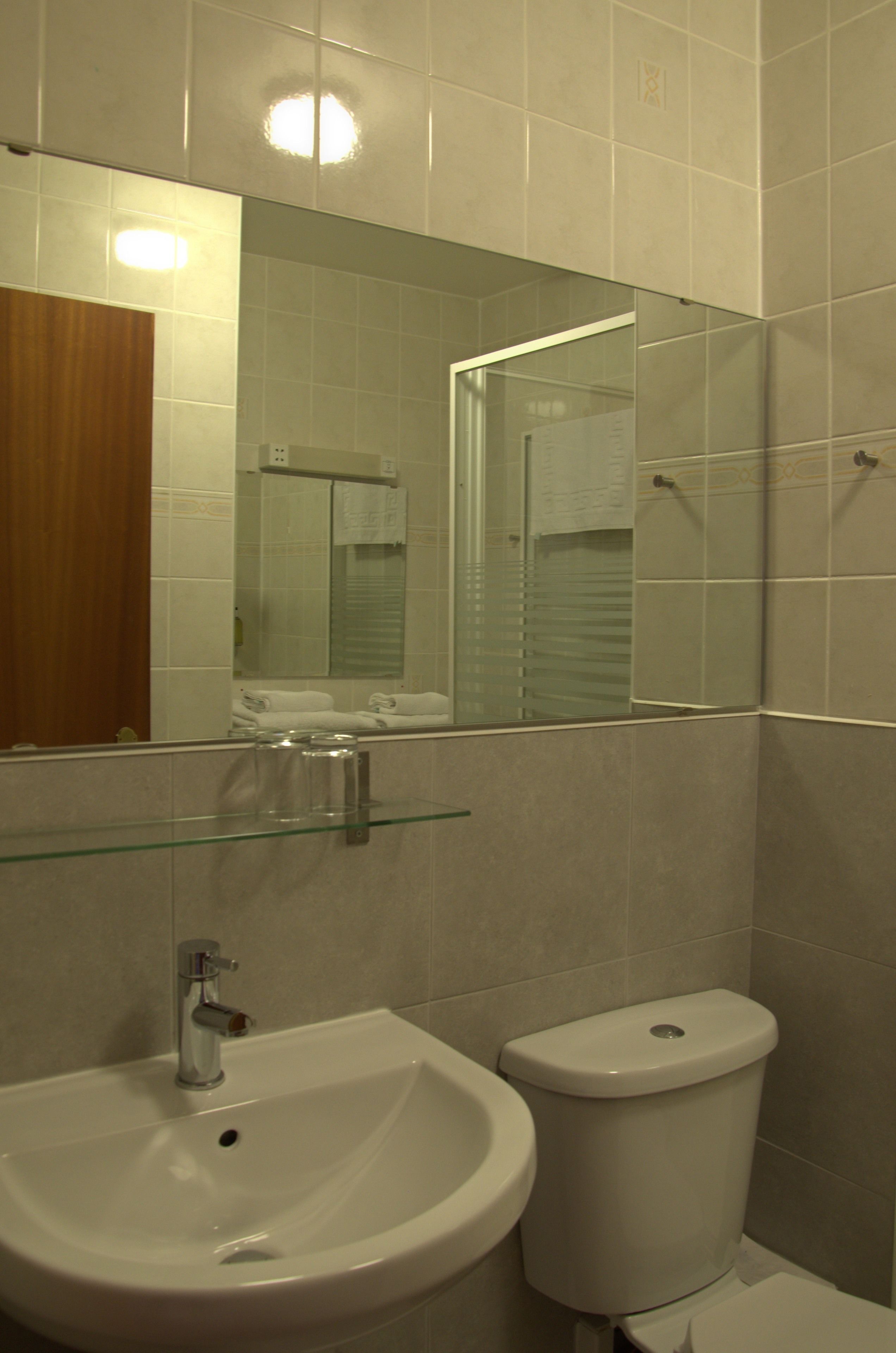 A bathroom with a sink, toilet, and a mirror.