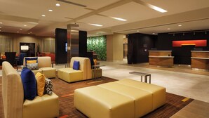 Un hall d’hôtel moderne, doté de sièges confortables, d’un comptoir d’accueil et d’un mur d’accent de couleur verte.