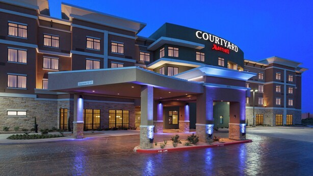 Un hôtel Courtyard Marriott au design moderne, doté d’une entrée couverte et de plusieurs étages.