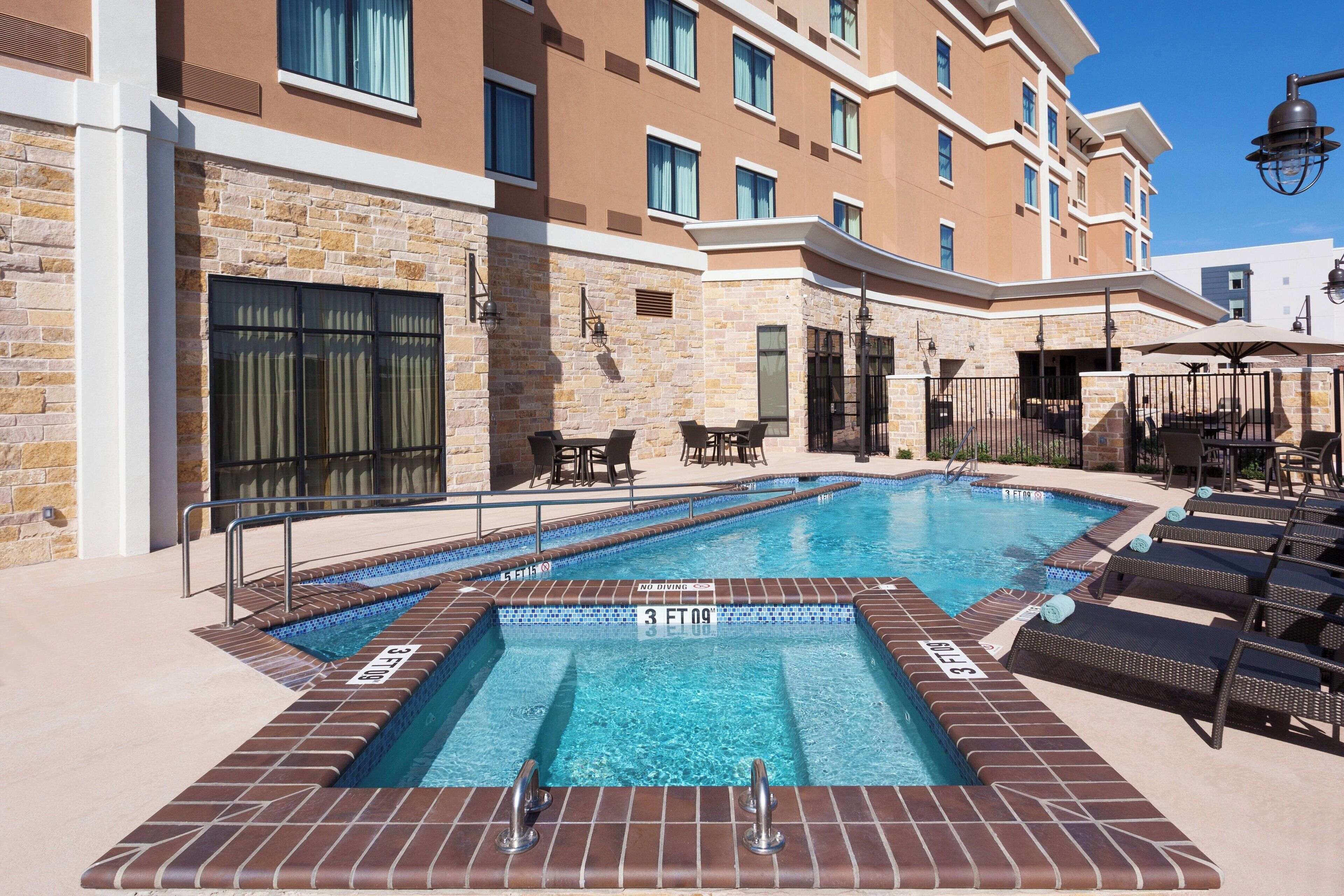 A swimming pool with lounge chairs and a stone wall.