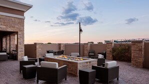 Une terrasse extérieure avec des murs en pierre, un foyer et des meubles en osier.