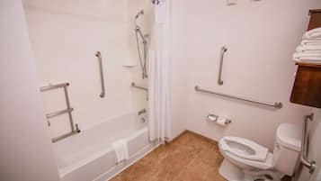 A bathroom with a bathtub, toilet, and shower. It includes grab bars and a handrail.