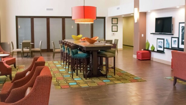 A spacious dining area with a long table, multiple chairs, and a colorful patterned rug. - Hampton Inn & Suites Dallas/Frisco North-FieldhouseUSA (Frisco)