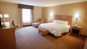 A hotel room with a large bed, a desk, a chair, a nightstand, and a lamp. - Hampton Inn & Suites Dallas/Frisco North-FieldhouseUSA (Frisco)