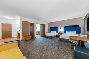 Una habitación de hotel con dos camas, un escritorio, una silla y una mesita.