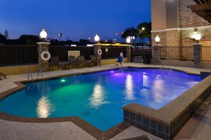 An outdoor swimming pool with a stone wall and a lifeguard sign. - Hampton Inn & Suites Dallas Market Center (Dallas)