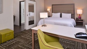 A hotel room with a bed, bedside lamps, a desk, a chair, a telephone, and a suitcase. - Hampton Inn & Suites Dallas Market Center (Dallas)