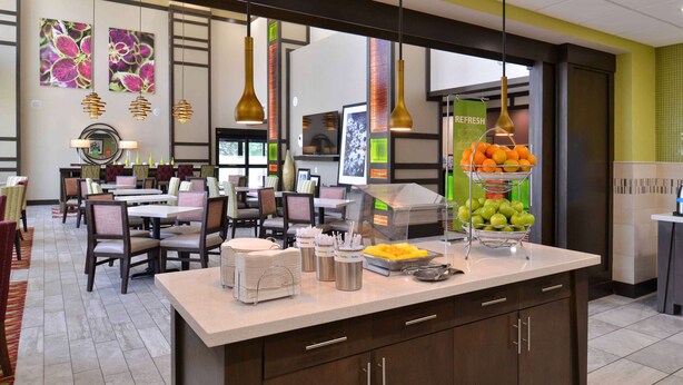 A modern hotel lobby with a central counter, seating area, and artwork on the walls. - Hampton Inn & Suites Dallas Market Center (Dallas)