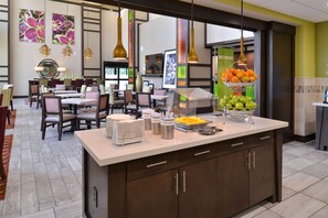 A modern hotel lobby with a central counter, seating area, and artwork on the walls. - Hampton Inn & Suites Dallas Market Center (Dallas)
