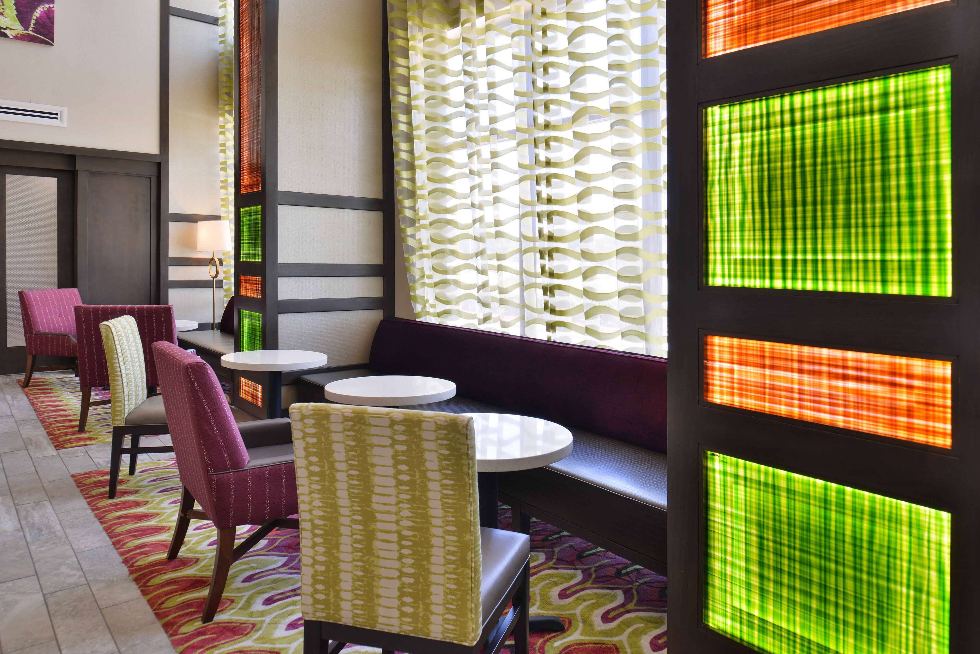 A hotel lobby with seating areas, tables, and decorative panels.