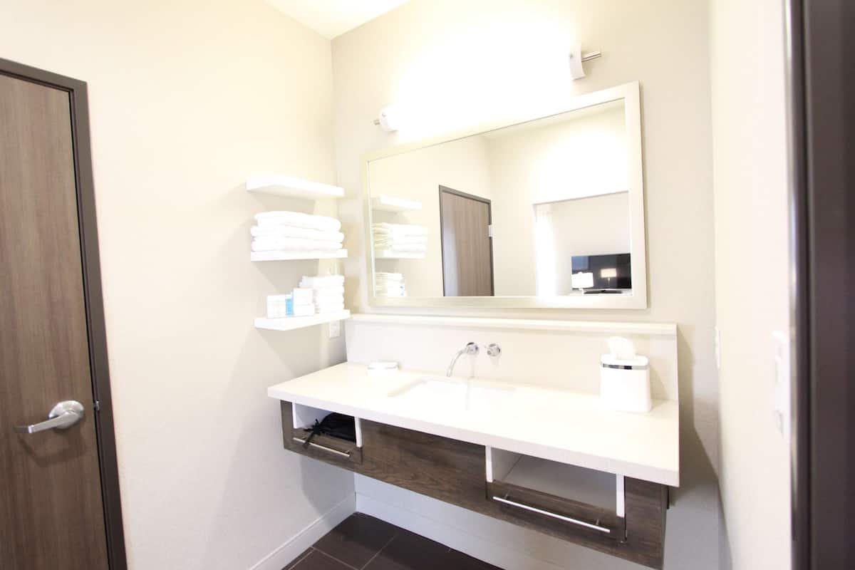 A bathroom with a white sink, a mirror, and a towel rack.