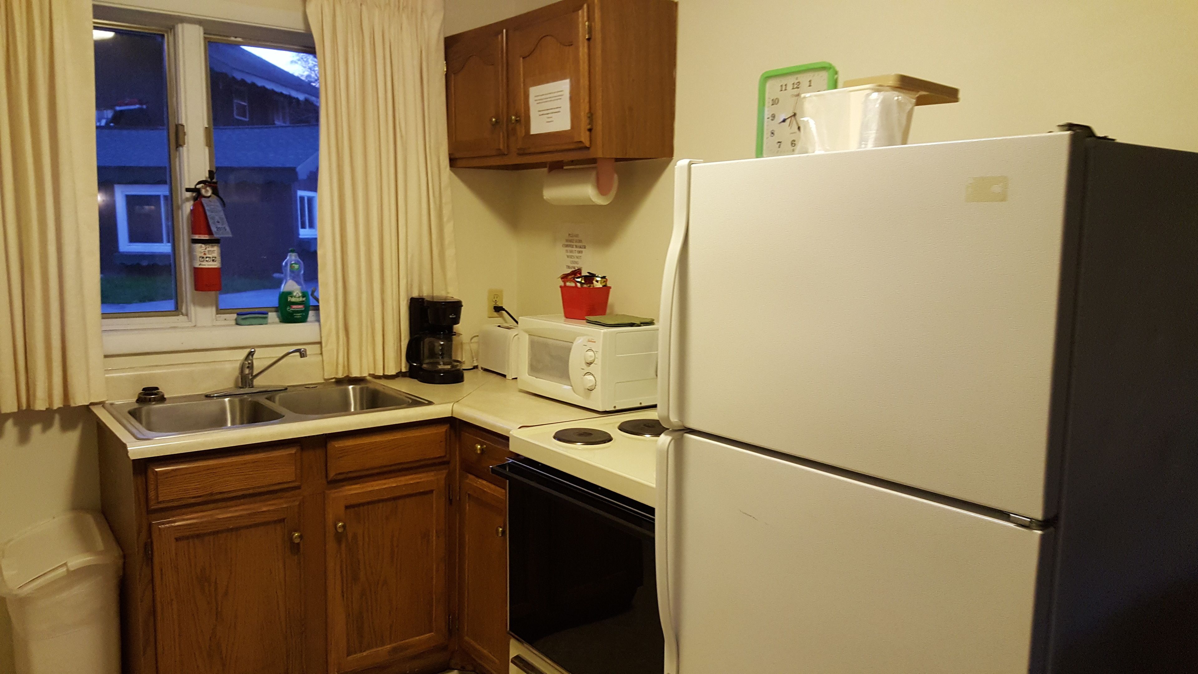 Una cocina compacta con lavamanos, microondas, tostadora y refrigerador.