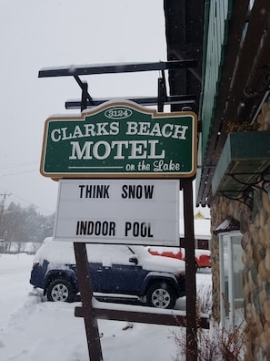 En skylt för ett motell med texten ”Clarks Beach Motel vid sjön” och ”Inomhuspool – tänk på snön!”.
