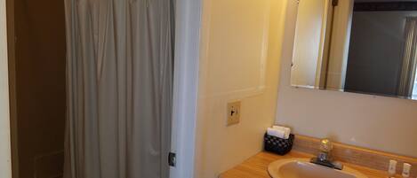 A bathroom with a shower curtain, a sink, a mirror, and a towel rack.