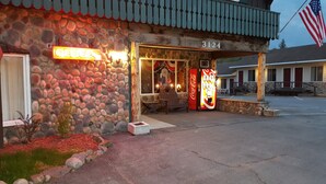A stone building with a Coca-Cola vending machine, a chair outside, and an American flag. - Clark's Beach Motel (Old Forge)