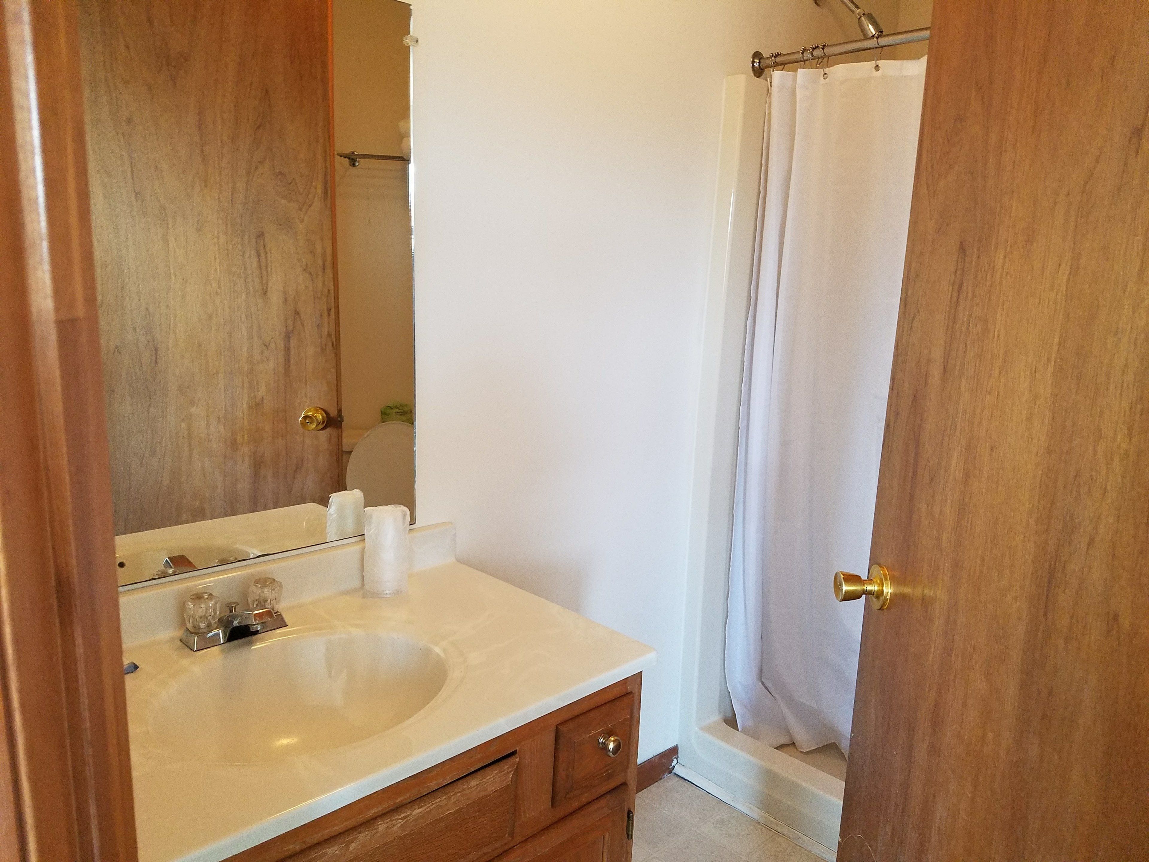 A bathroom with a wooden vanity, a sink, and a shower curtain.
