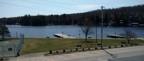 A parking lot with marked spaces, a grassy area with benches, and a lake with a dock.
