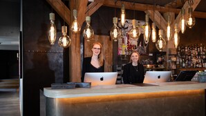 En reception med to medarbejdere, trælofter og en bar i baggrunden.