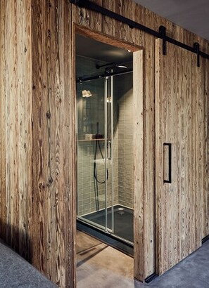 A modern shower with glass doors, wooden paneling, and a black handle. - Landhaus Flottbek (Hamburg)