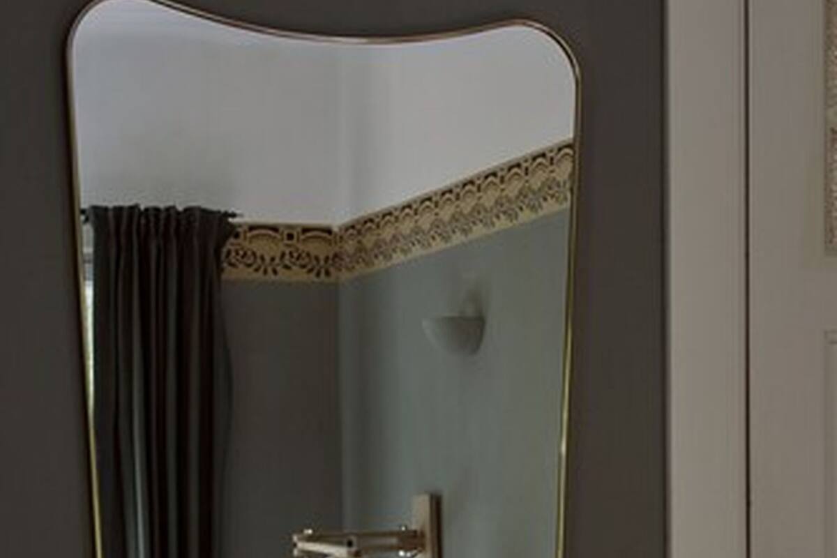 A bedroom with a bed, a bedside lamp, and a mirror on the door.