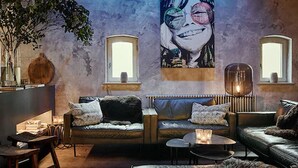 En hyggelig stue med en sofa, et sofabord og en pejs. Der er et billede på væggen og et vindue med udsigt.