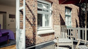 En murstensbygning med et hvidt vindue og en træterrasse.