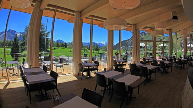 A restaurant with large windows offering mountain views, wooden ceiling beams, and multiple tables and chairs. - Hotel Royal (Riederalp)