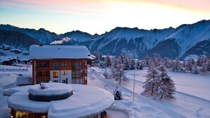 A snow-covered mountain landscape with a lodge featuring a large wooden building and a circular structure. - Hotel Royal (Riederalp)