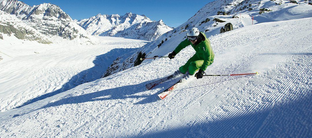 A skier on a snowy slope with mountains in the background.