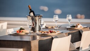 Een eettafel met borden eten, wijnkaraffen en een champagnefles.