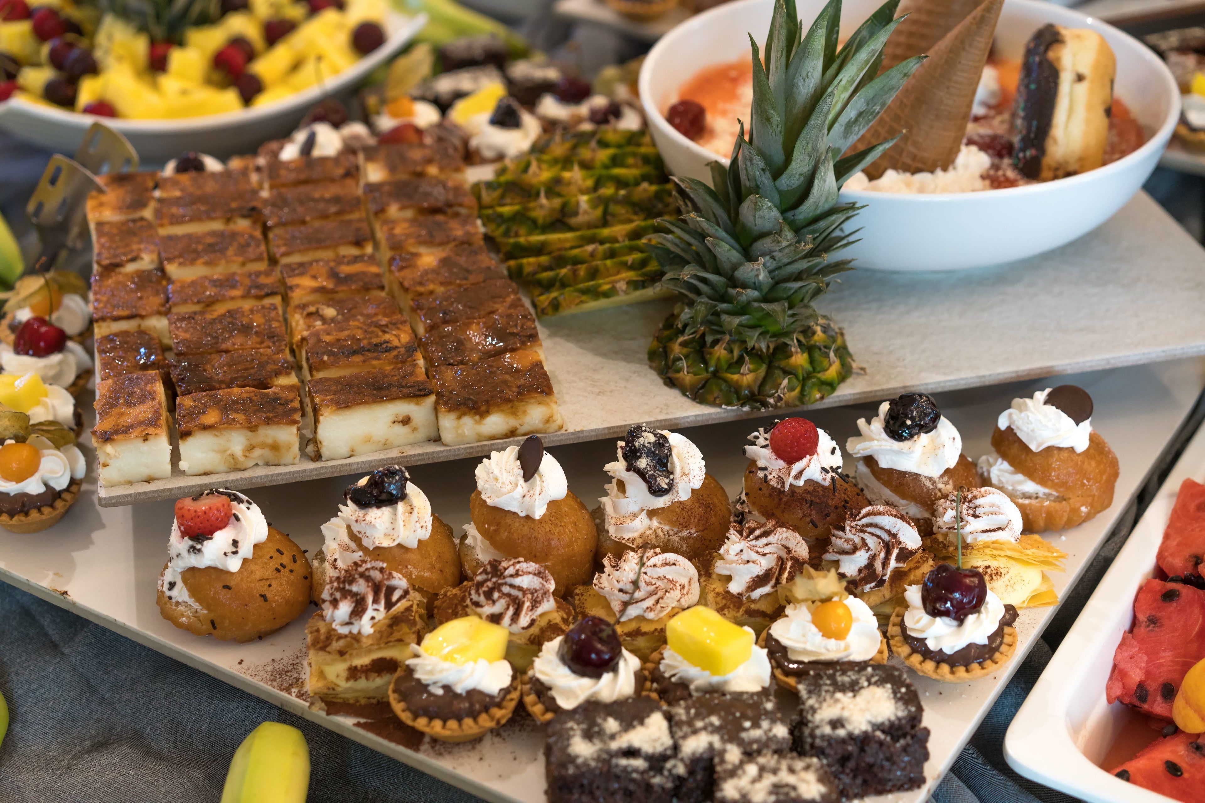 A variety of desserts including cakes, pastries, and fruit on a buffet table.