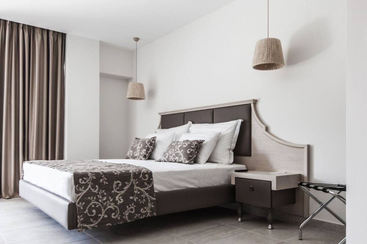 A modern bedroom with a large bed, a nightstand, and a hanging lamp.