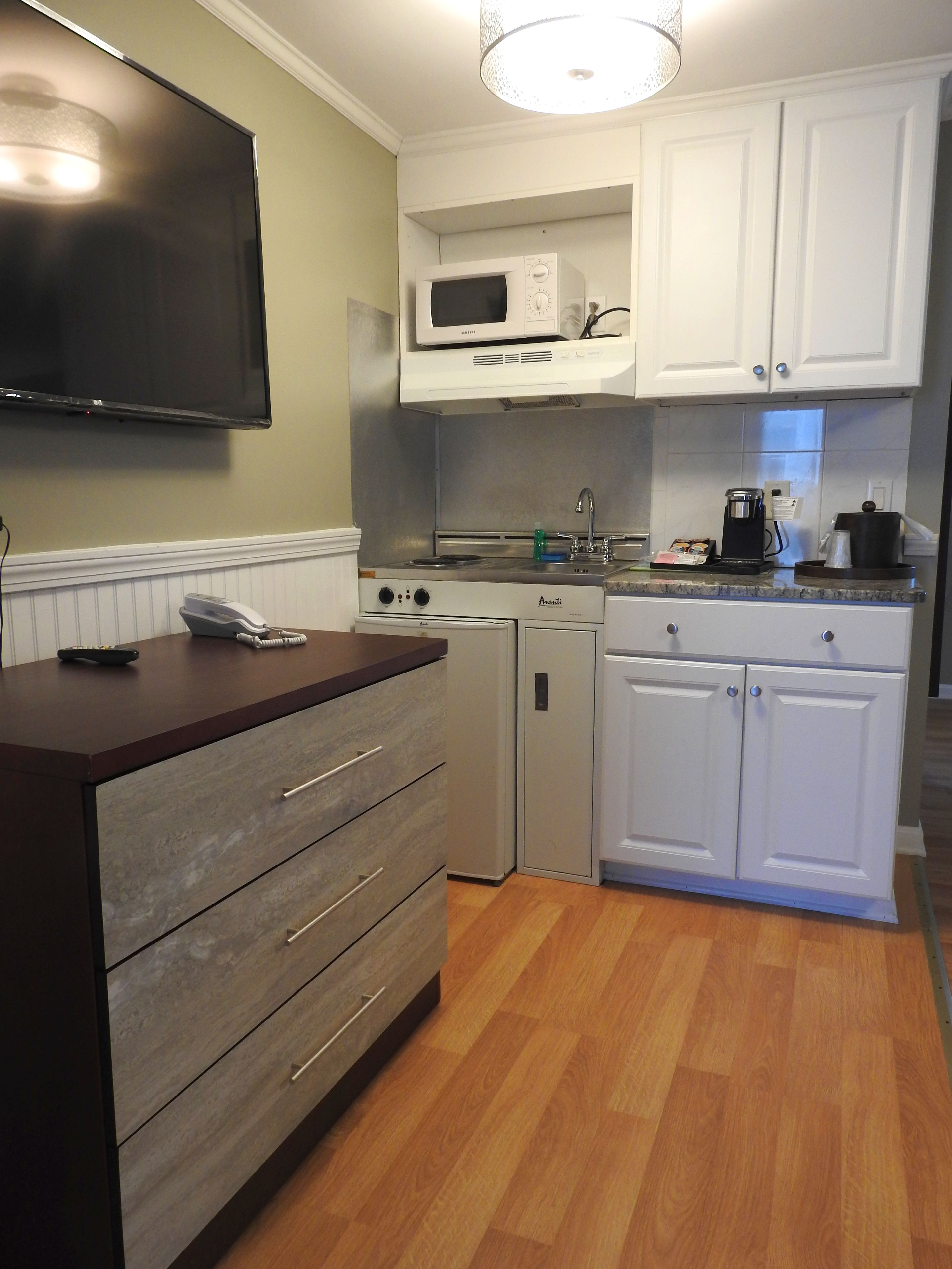 A compact kitchen with a microwave, stove, and coffee maker.