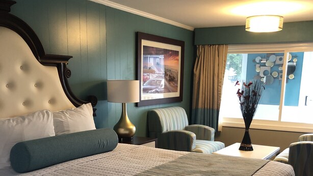 Una habitación de hotel con una cama grande, una silla, una mesa y una ventana con cortinas.
