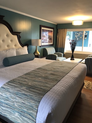Una habitación de hotel con una cama grande, una silla, una mesa y una ventana con cortinas.