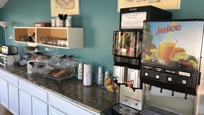 Una estación de café con dispensador de jugo de la marca Bunn, una máquina de café y una variedad de cápsulas de café.