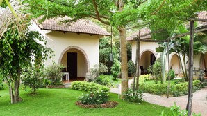 A courtyard with a building featuring arched doorways and a tiled roof. - Diadem Resort (Phu Quoc)