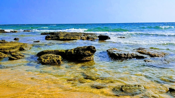 A beach with clear water, rocks, and a clear sky. - Diadem Resort (Phu Quoc)