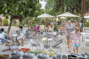 An outdoor dining area with tables and chairs, surrounded by greenery and umbrellas. - Diadem Resort (Phu Quoc)