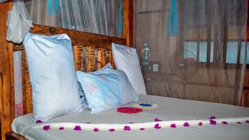 A bed with white linens, a wooden headboard, and a mosquito net.
