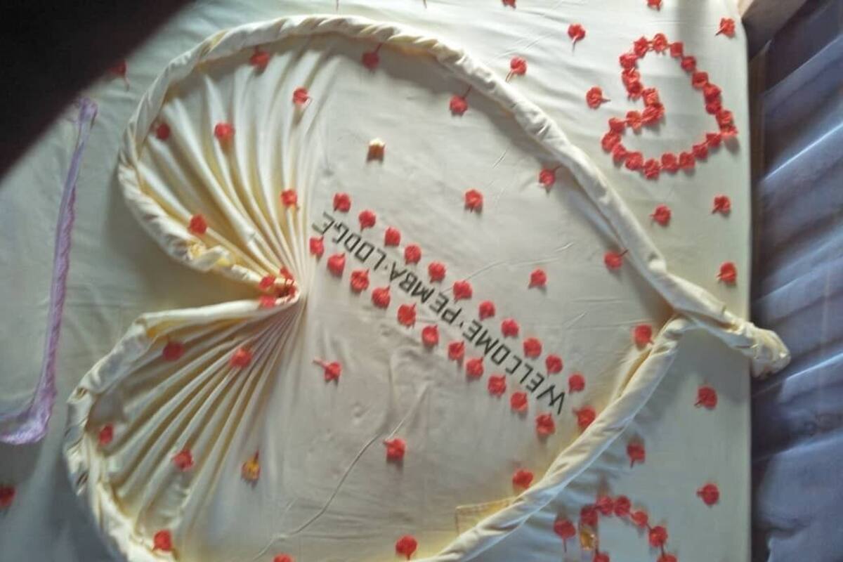 A bed with a white sheet and red floral decorations.