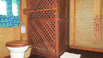 Traditional Japanese bathroom with a wooden lattice partition, white toilet, and woven bamboo mat.
