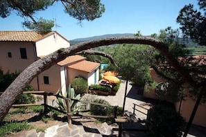 A rustic outdoor area with a stone staircase, a wooden pergola, and a view of a building with a tiled roof.