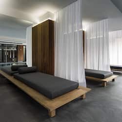 Two platform beds flank sheer white curtains, offering a view of the outdoors through a large window.