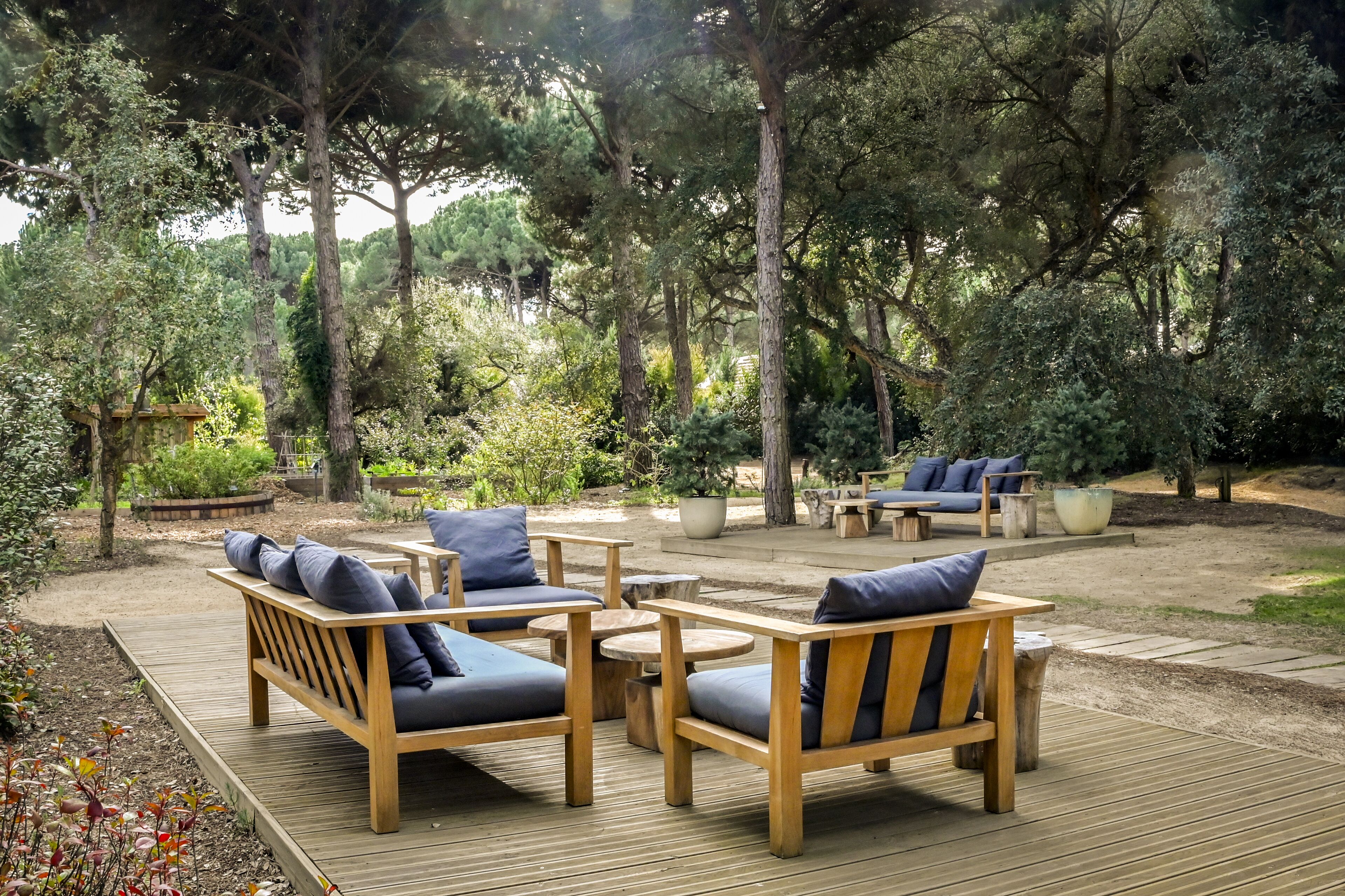 An outdoor patio with wooden furniture and a view of a forested area.